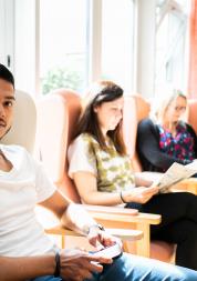 Three people sitting in some chairs in a waiting area